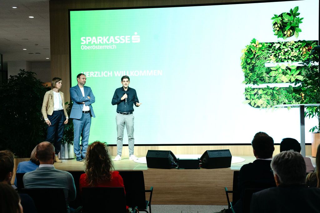 Begrüßung auf der Bühne der s Begegnungszone der Sparkasse Oberösterreich beim 5. Sustainability Cycle OÖ, im Vordergrund das Publikum